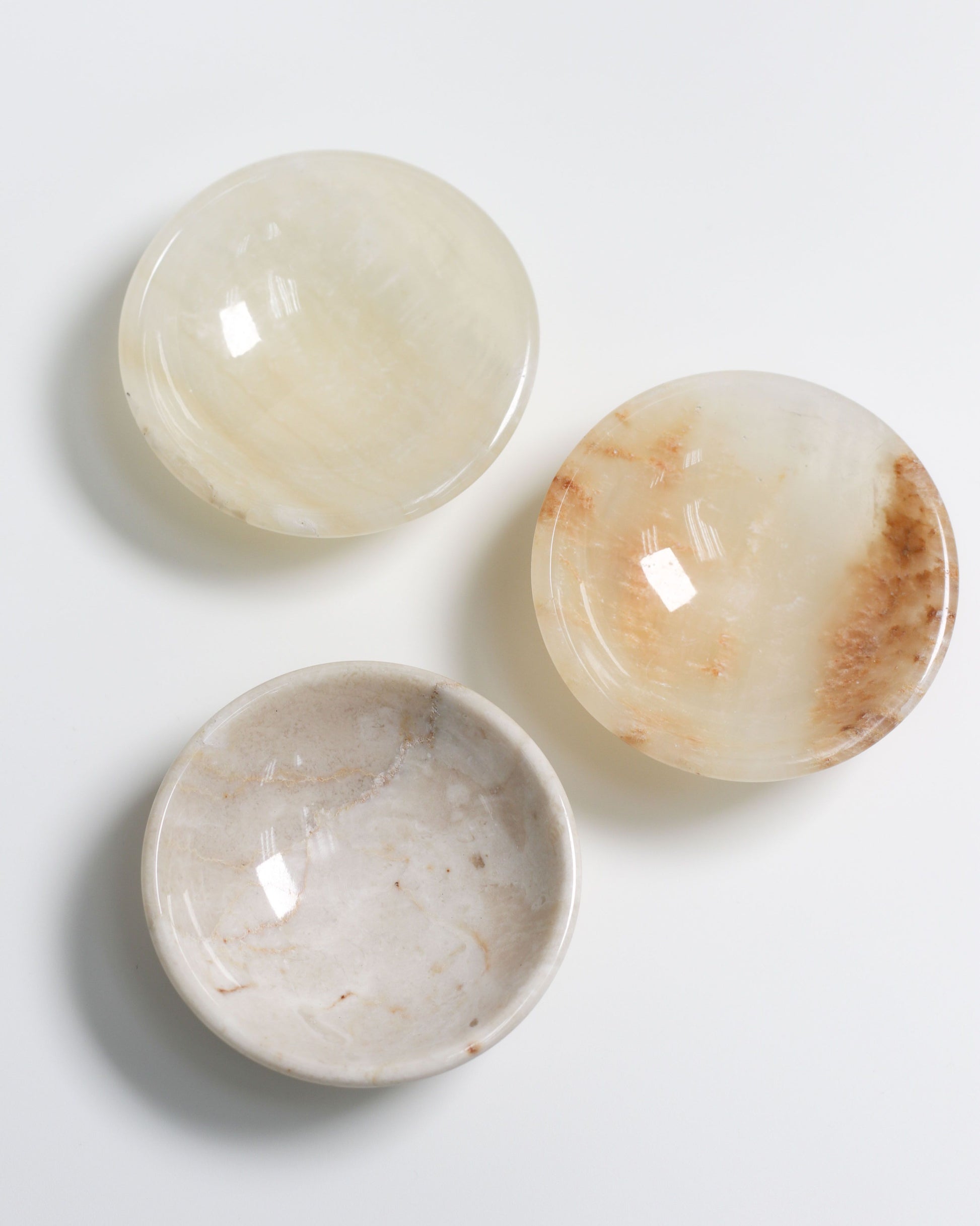 The stillgoods Luna Dish set by stillgoods features three round, shallow catch-all dishes with smooth, polished off-white and beige surfaces—ideal as mini trinket dishes for your essentials.