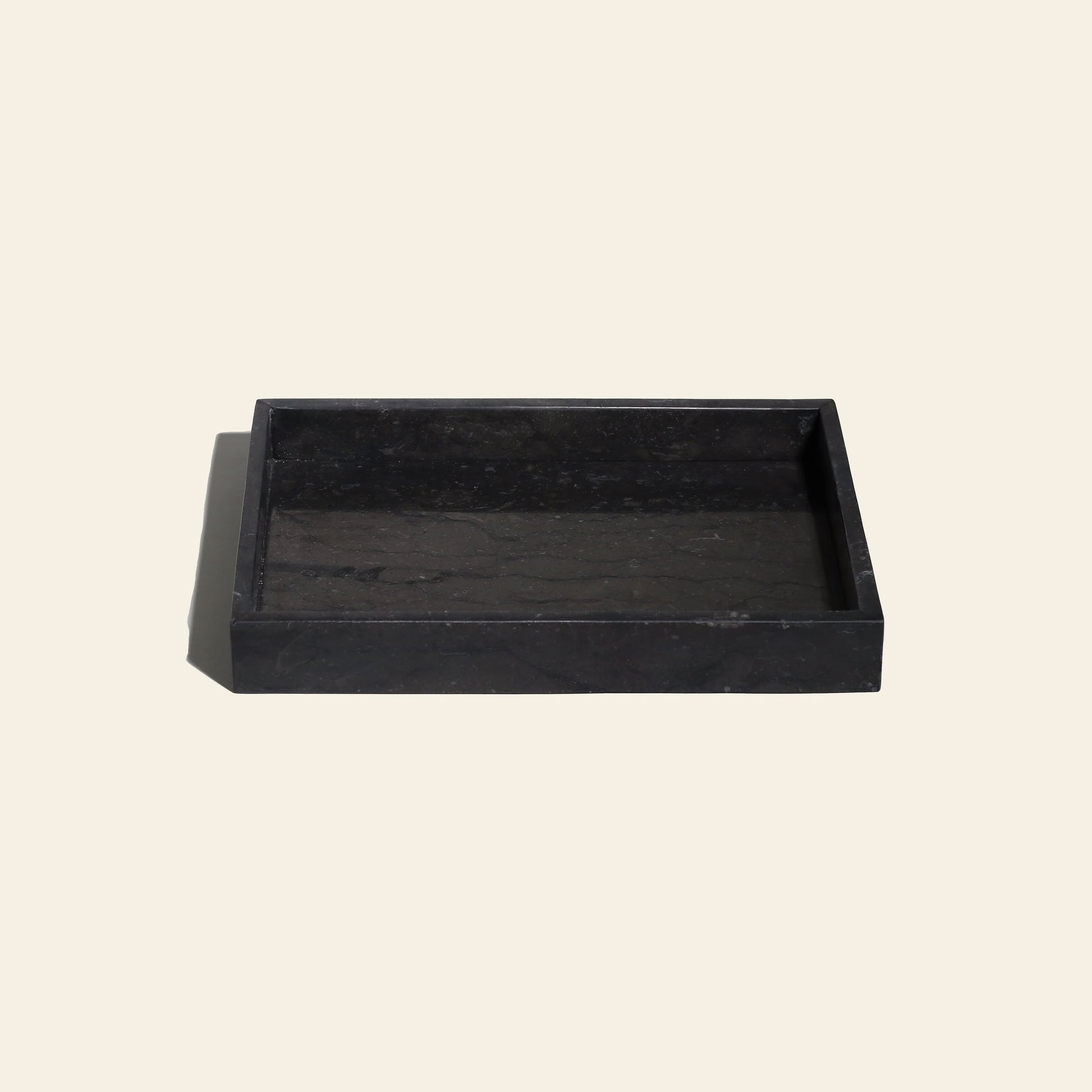 The stillgoods Mini Valor Tray is a rectangular black tray with a low-profile design and raised edges, ideal for organizing essentials. Crafted from solid material by stillgoods, it looks sleek on any light-colored surface.