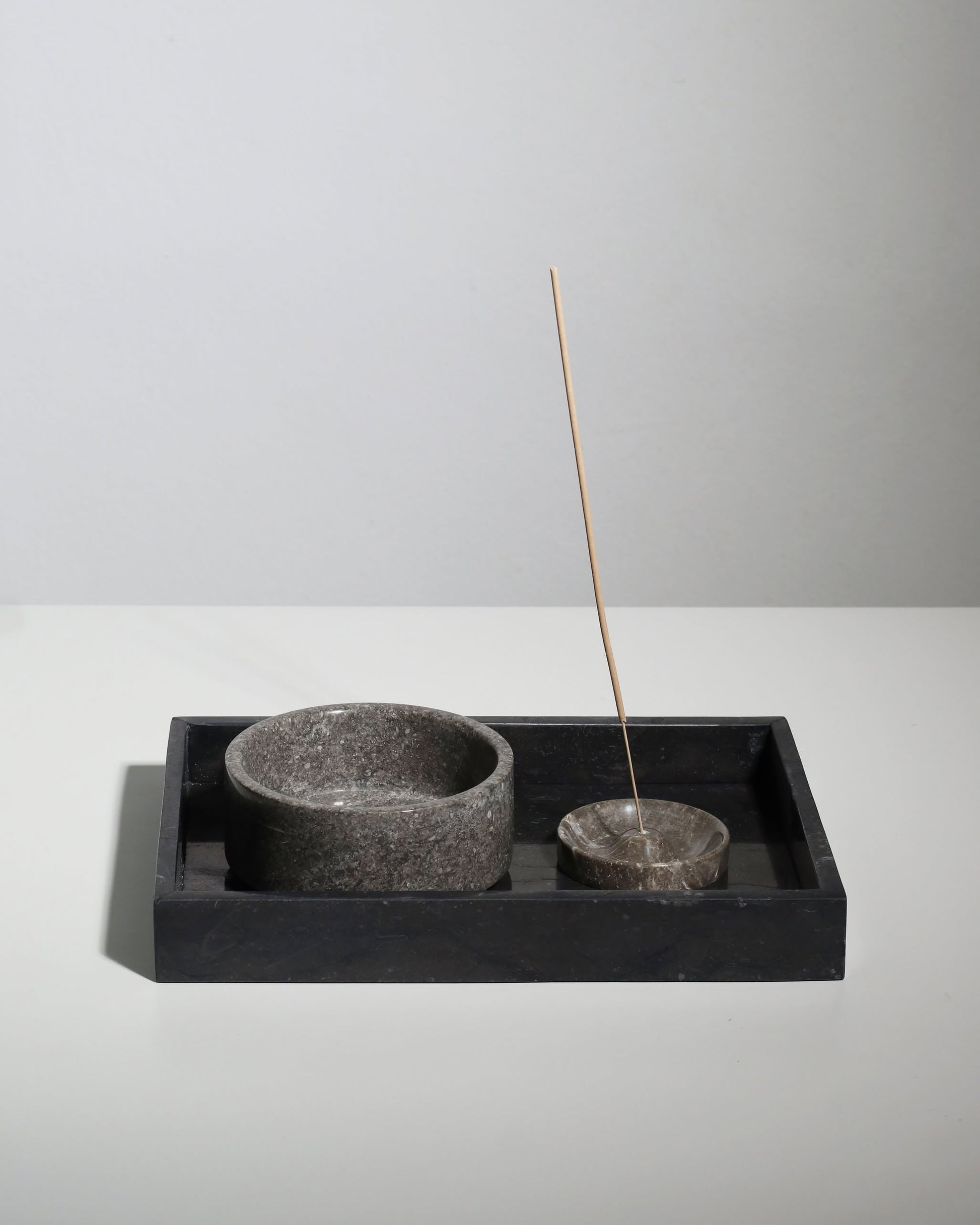A stone incense holder with a lit stick and a matching round bowl rest on the stillgoods Mini Valor Tray, whose low profile stylishly displays your essentials against a plain light background.