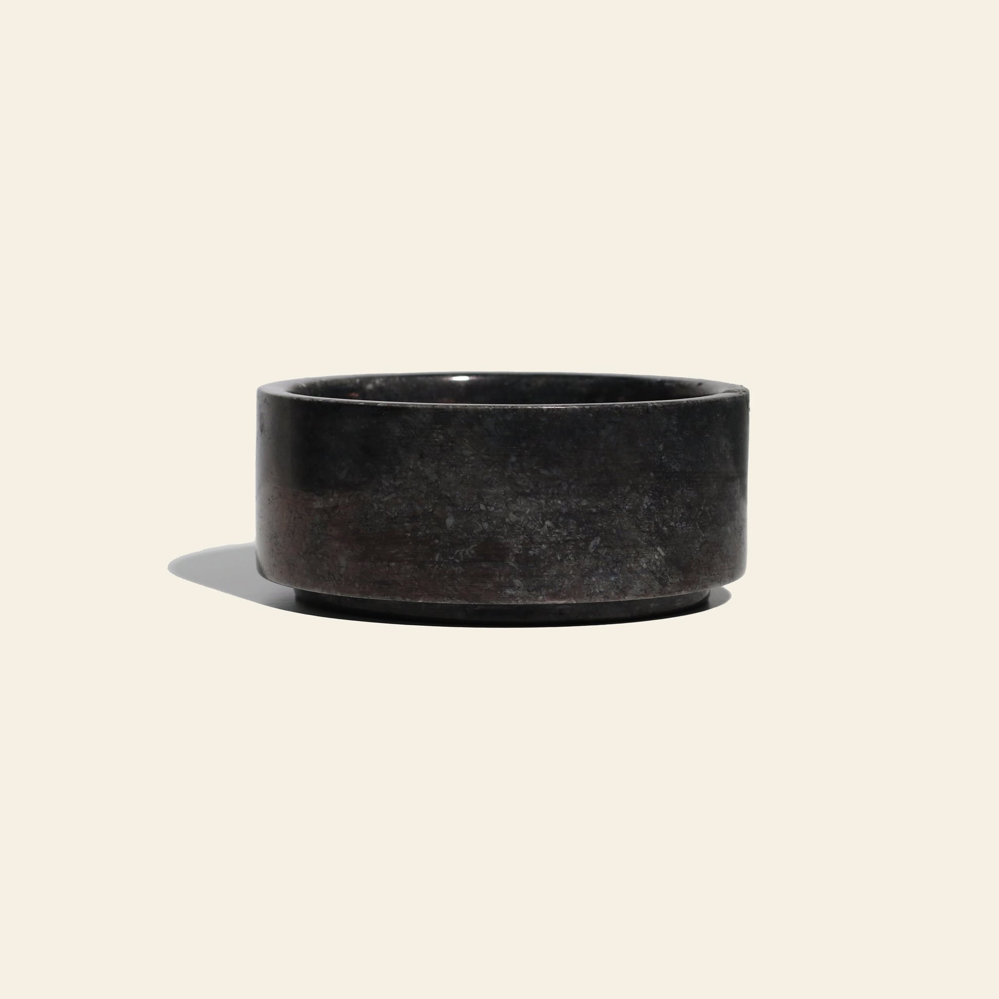 The stillgoods Tingkat Bowl—a round, black onyx bowl with a smooth surface—rests on a light beige background, casting a soft shadow to the left.