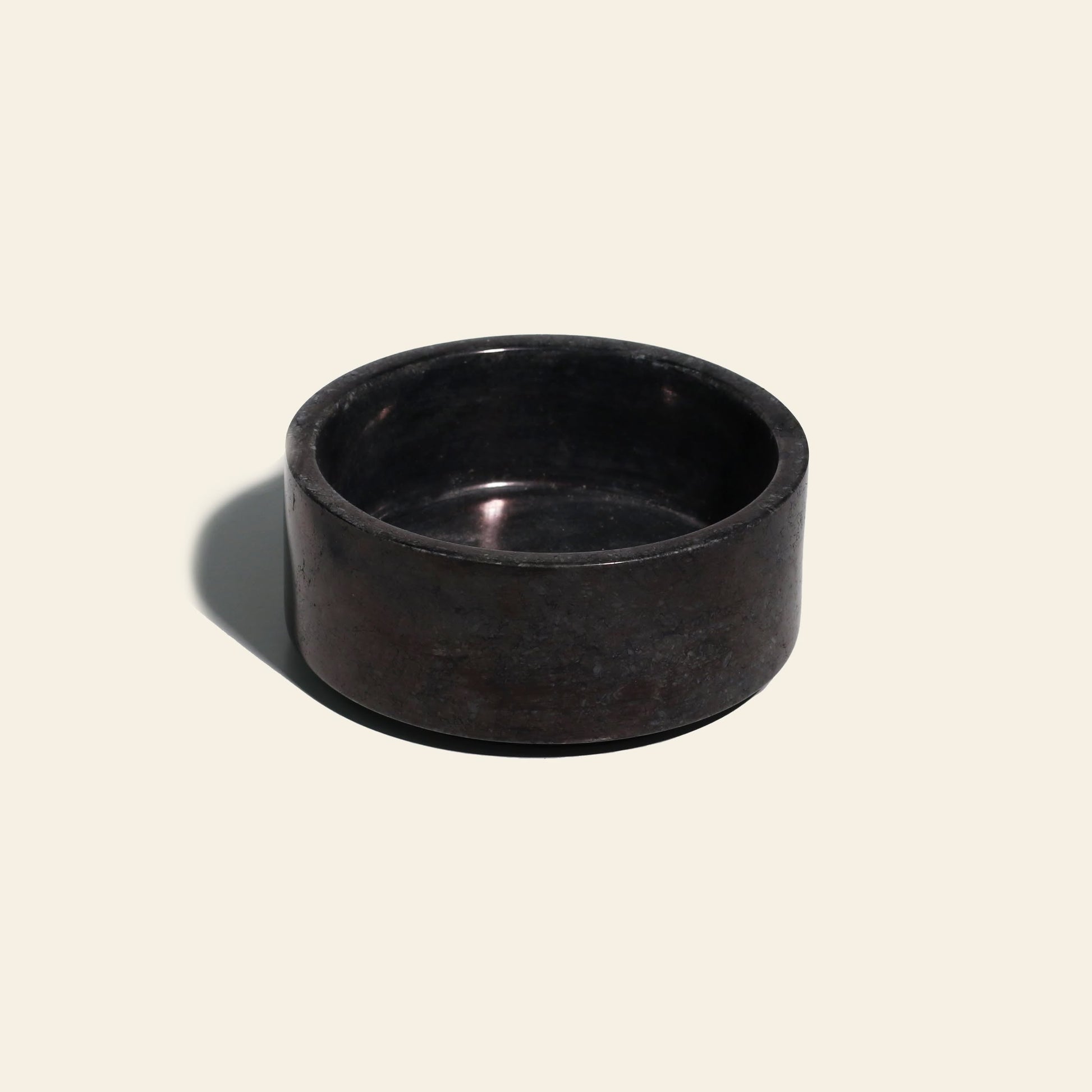 The stillgoods Tingkat Bowl is a small, round bowl made of black onyx marble with thick sides, displayed on a light beige background with a shadow to the left.