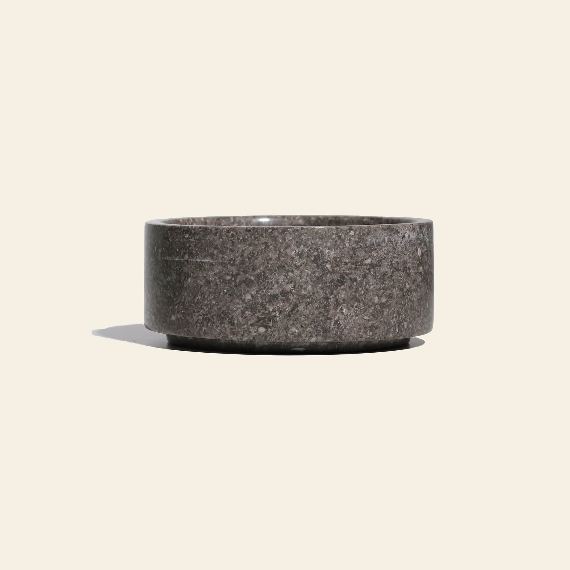 The stillgoods Tingkat Bowl, featuring a smooth, round design in dark gray onyx, is centered against a plain light beige background, casting a soft shadow to the left.