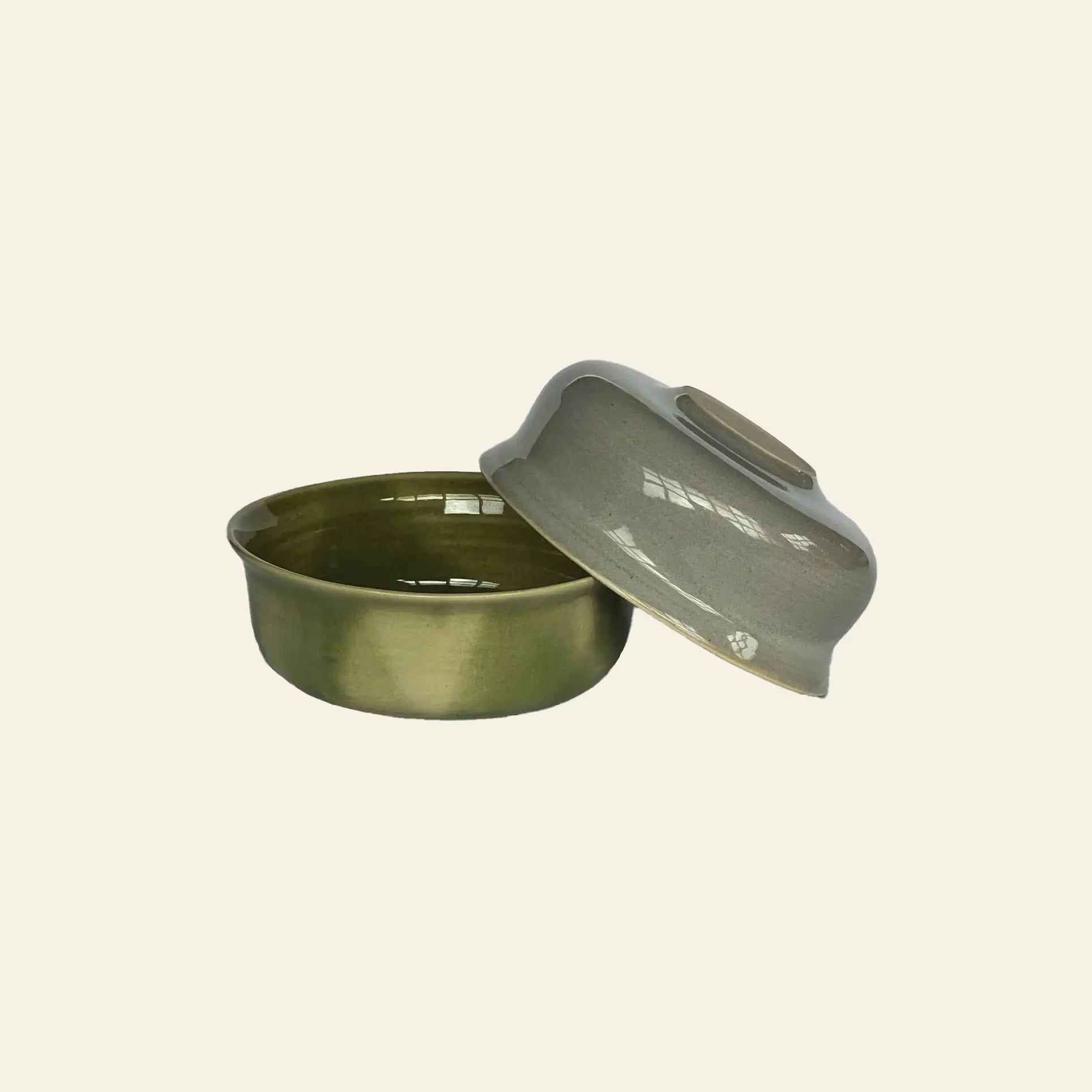 The ves Aki Bowl, Set of 2 by ves features round, olive-green ceramic bowls with matching lids, a glossy finish, and handcrafted details inspired by classic East Asian tableware, set against a simple light background.