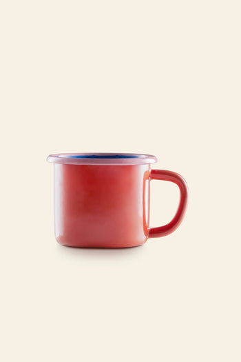 The Bornn Enamelware Colorama Mug by Bornn Enamelware features a vibrant red exterior, blue inside rim, and handle—perfect for coffee—displayed against a plain beige background.