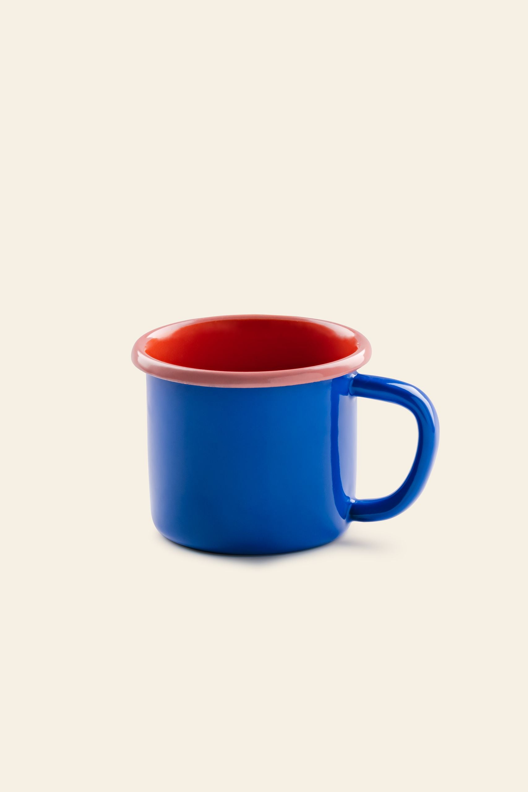 The Bornn Enamelware Colorama Mug by Bornn Enamelware features blue enamel with a red interior and rim, plus an easy-grip handle—an eye-catching addition to any mug collection. Set against a simple light beige background.