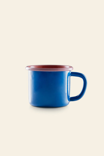 The Bornn Enamelware Colorama Mug by Bornn Enamelware features a blue finish with a red-rimmed top and handle, displayed on a plain beige background.