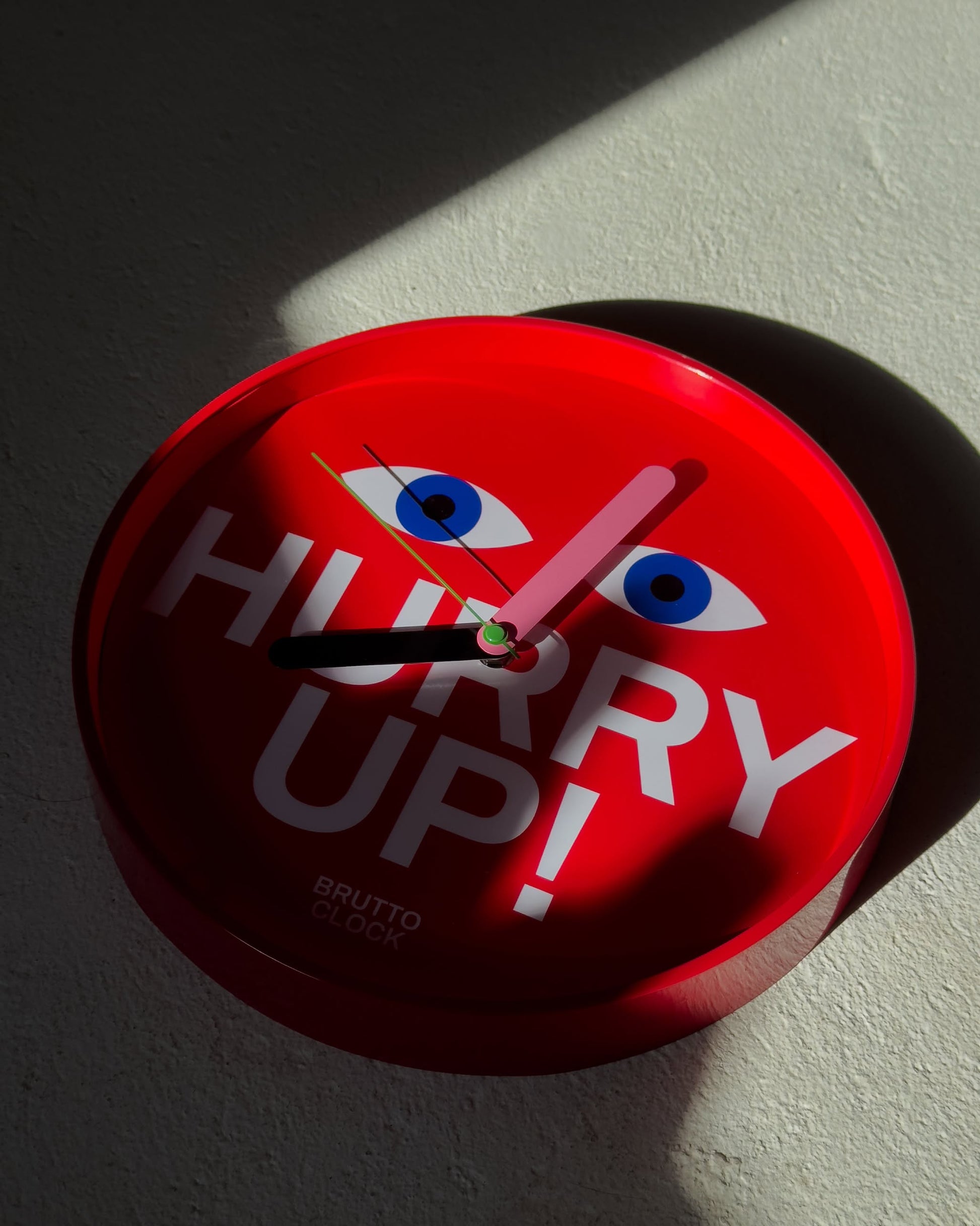 The Brutto Studio Hurry Up! Wall Clock - Multicolour features blue eyes, bold white lettering on a red face, displays 10:09, and uses silent quartz movement for noiseless precision—a stylish accent by Brutto Studio.