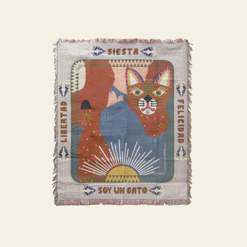 The DETAIL Cat Oax Throwket by DETAIL is a colorful folk art blanket with a cat, sun rays, and abstract shapes. Spanish words like Libertad, Siesta, Felicidad, and Soy un gato border the fringed cat throw blanket.
