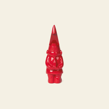 The DOIY Gnome Bottle Opener by DOIY, a small, shiny red figurine with a tall pointed hat and folded arms, is displayed on a plain light beige background.