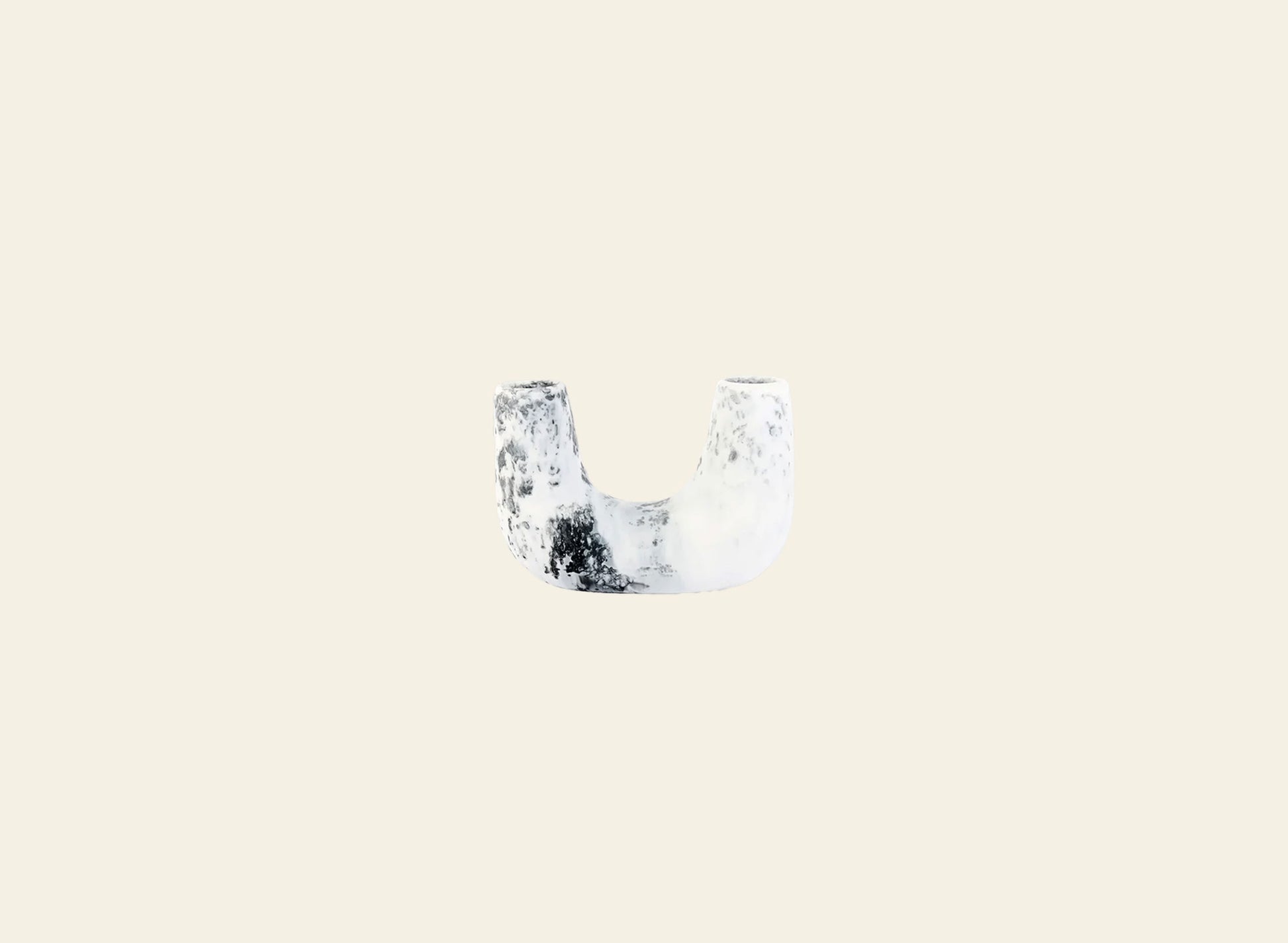 A small, white, U-shaped Dinosaur Designs Mini Branch Vase with a rough texture and black speckles is centered on a plain beige background.