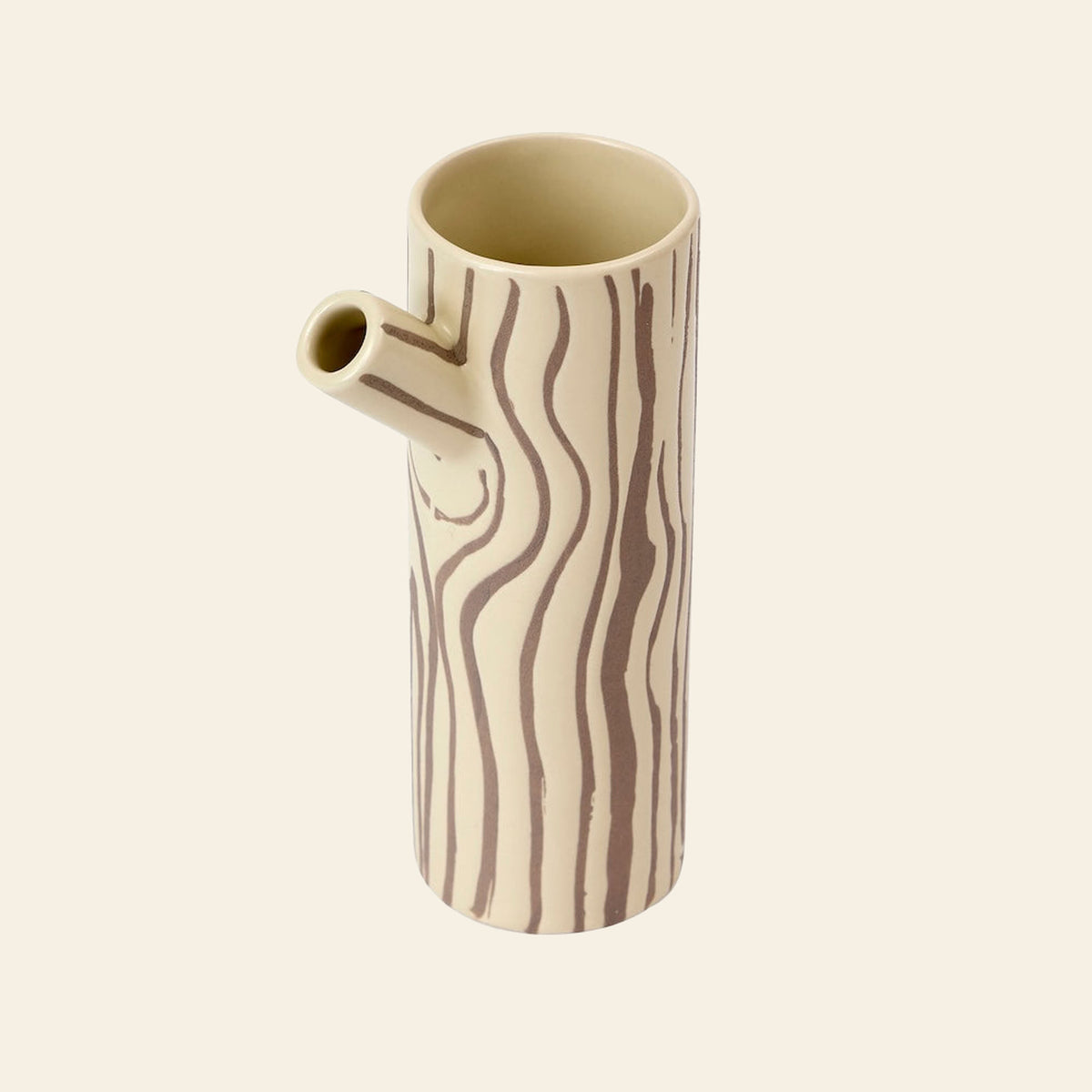 Donna Wilson Small Log Jug / Vase, a cylindrical stoneware piece with a spout, featuring a cream-colored body with brown, tree-ring style line patterns that evoke a woodland charm.