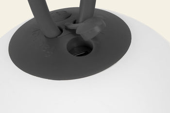 Close-up of the Fatboy Bolleke by Fatboy: a black rubber cap with two handles on a round white portable light, featuring a central opening—perfect for creating ambient outdoor lighting.