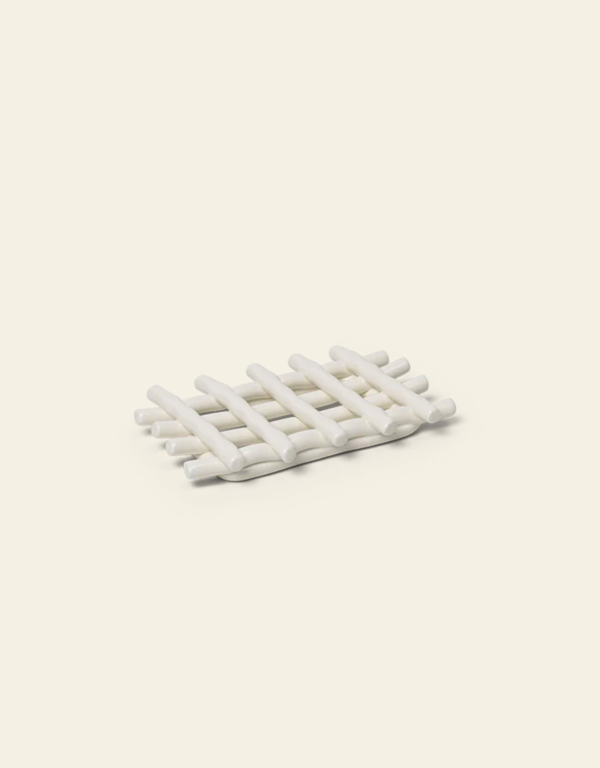 The Ferm Living Ceramic Soap Tray in off-white, featuring a lattice design, is an elegant bathroom accessory from Ferm Living, shown here on a light beige background.