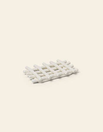 The Ferm Living Ceramic Soap Tray in off-white, featuring a lattice design, is an elegant bathroom accessory from Ferm Living, shown here on a light beige background.