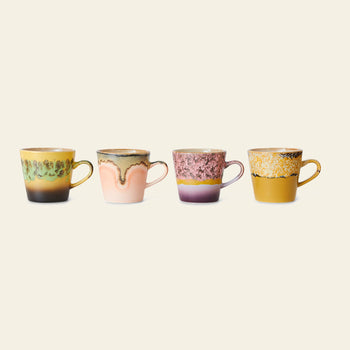 The HKliving 70s Ceramics: Americano Mugs, Set of 4 features vibrant retro-inspired designs in yellow, pink, green, and purple. Each HKliving mug boasts a unique pattern and is displayed side by side against a light beige background.