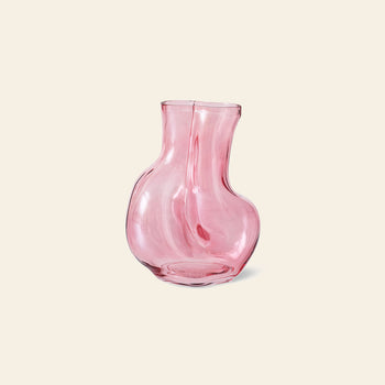 The HKLIVING Gleam Glass Vase by HKLIVING is a pink, translucent piece with a wavy, rounded shape and narrow opening—an eye-catching decor accent displayed on a light beige background, ideal for modern spaces.