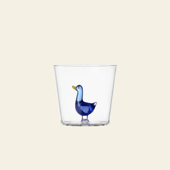 The Ichendorf Milano Animal Farm Tumbler by Ichendorf Milano features a clear glass design with a small blue glass duck inside, shown against a plain light beige background.