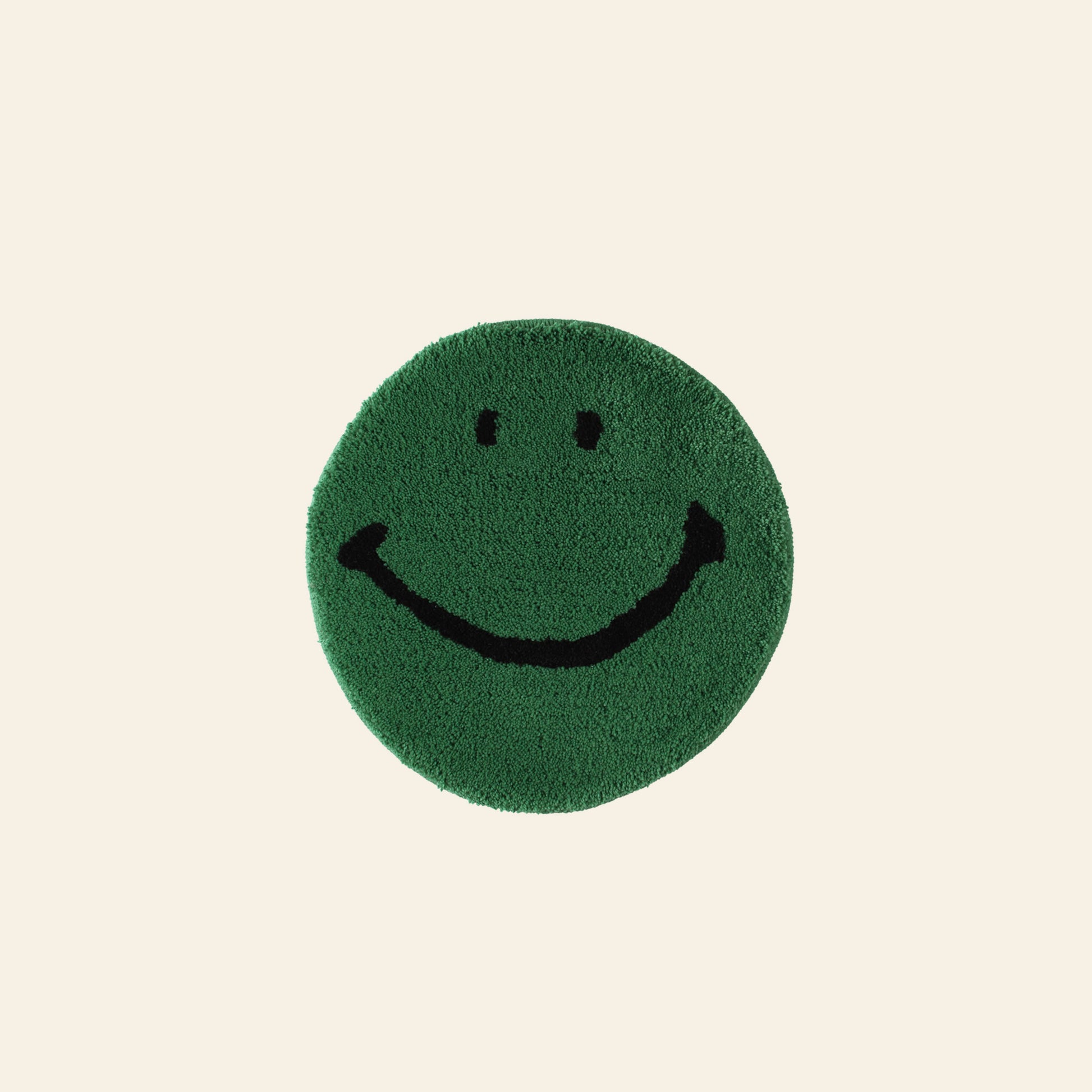 The MIYOSHI RUG Harvey Ball x MIYOSHI RUG Original Smiley Face Chair Rug features a green circular design with a simple black smiley face, inspired by Harvey Ball, on a light beige background.