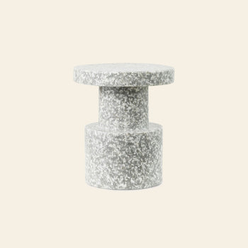 A Normann Copenhagen Bit Stool with a cylindrical base, a narrower center column, and a circular top, featuring a grey and white speckled finish.