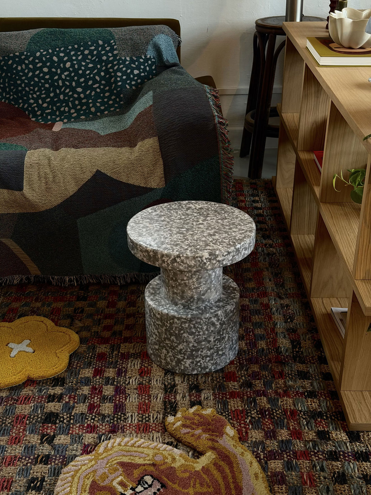 A Normann Copenhagen Bit Stool with a wide, circular seat in a speckled grey and white pattern, standing on a patterned rug.