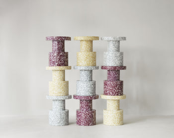 Three vertical stacks of sculptural Normann Copenhagen Bit Stools with a speckled, multicolored pattern.