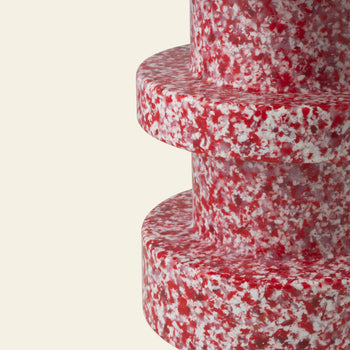 The Normann Copenhagen Bit Stool Stack by Normann Copenhagen features three round, stacked tiers in a red and white speckled pattern, offering modern, versatile seating for minimalist spaces.