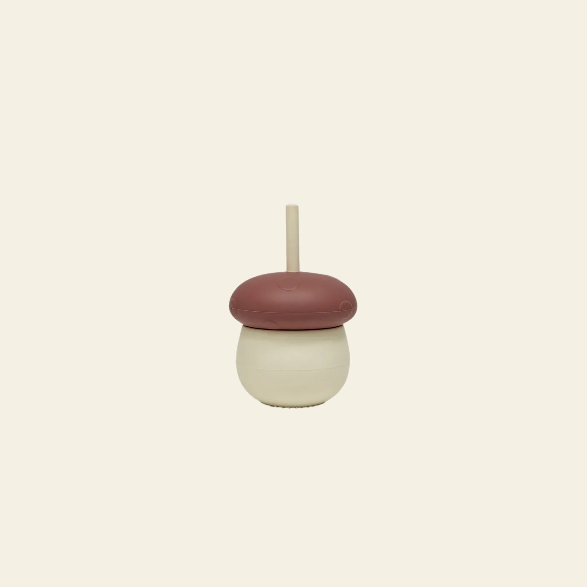 The OYOY Living Design Mushroom Cup by OYOY Living Design features a playful beige base, a brown dome lid resembling an acorn cap, and a beige straw—an adorable silicone cup displayed on a plain off-white background.