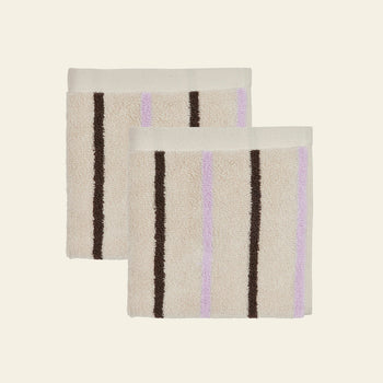 Two beige OYOY Living Design Raita Wash Cloths, made from organic cotton terry with vertical brown and light purple stripes, are shown side by side on a plain light background. Sold as a pack of 2.
