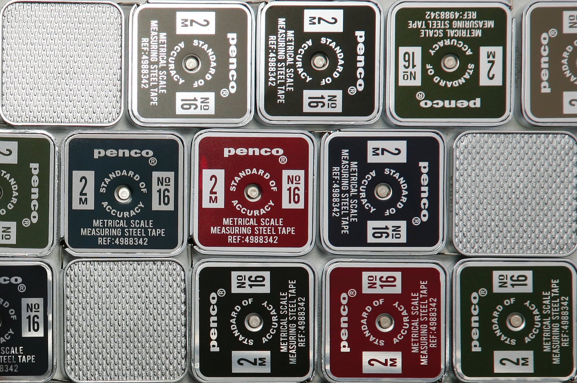 A close-up of neatly arranged Penco Pocket Measure tapes in compact metal cases—silver, green, red, and black—each labeled with measurement details and model info.