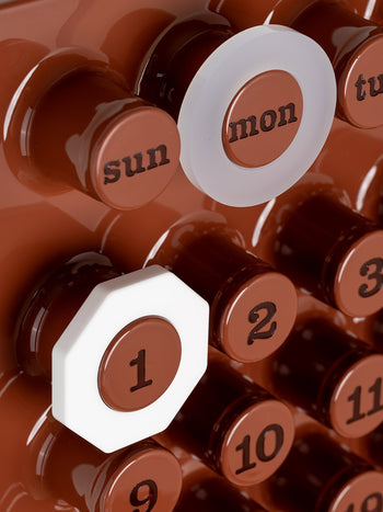 Close-up of the Ring-A-Date Limited Edition Wall Calendar - Cafè Mousse: brown with raised circular buttons for days and numbers; sun and mon are visible, with mon and 1 outlined in white. Brand: Ring-A-Date.