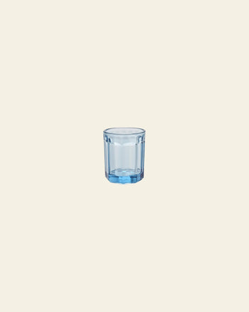 A small, transparent blue Serax Fish & Fish Glass M by Serax is centered on a plain, light beige background, its cool hue inspired by the brand’s iconic collection.