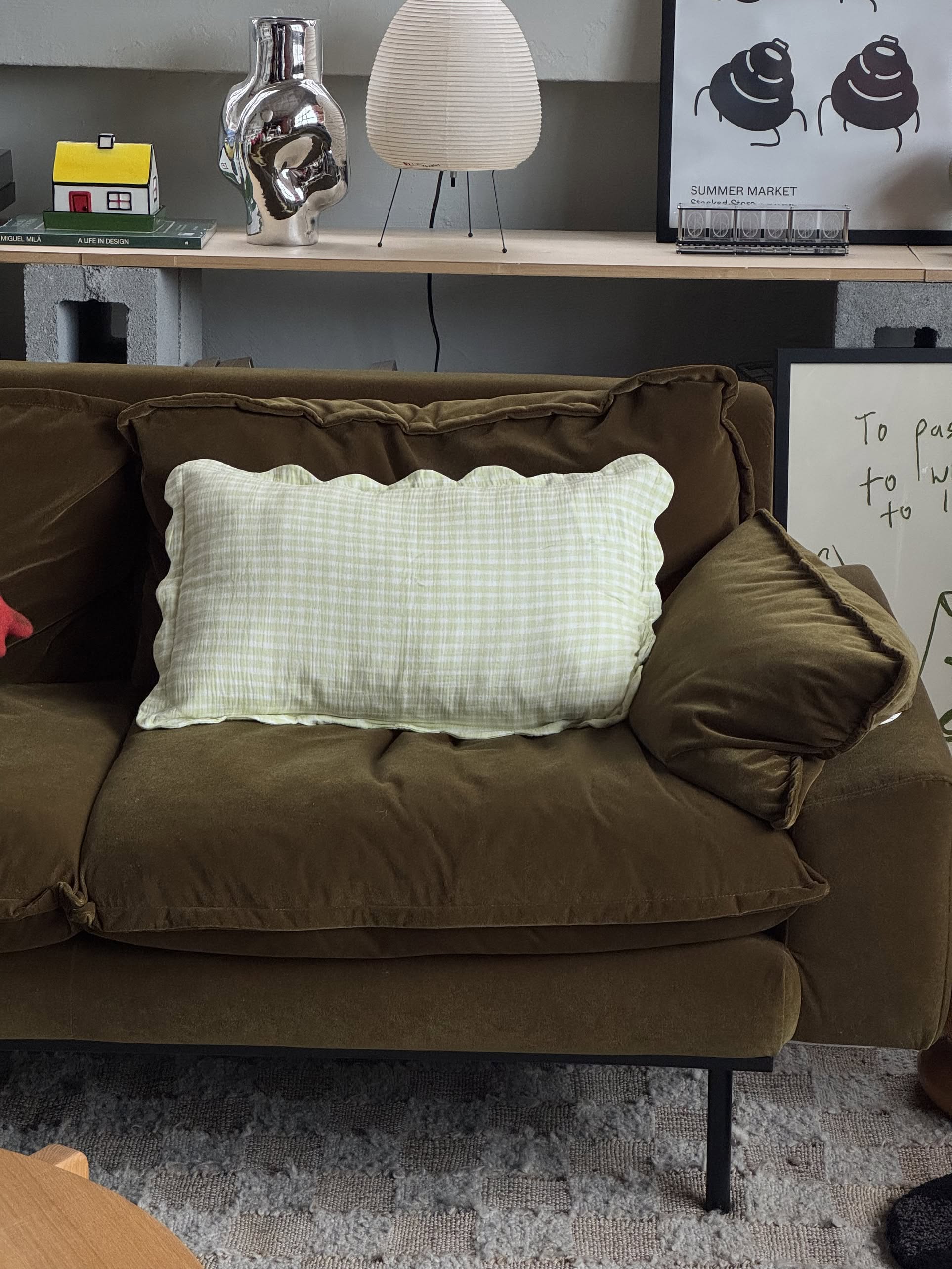 A brown velvet sofa features a large pillow with Soft Spot Soft Petal Cushion Covers Rectangle, Set of 2. Behind the sofa is a shelf holding decorative items like a lamp, a small yellow house, and framed artwork.