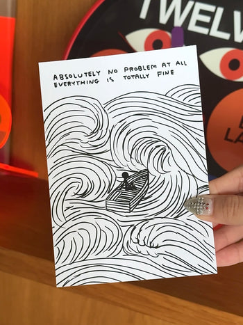 A hand holds the Stacked Store No Problem At All Gift Card (Physical), featuring a David Shrigley illustration of a person in a rowboat amid waves. The card reads, "Absolutely no problem at all, everything is totally fine"—great for gifting.