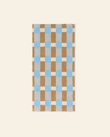 The WARMGREY TAIL Dot Check Face Towel is a rectangular cotton terry towel featuring a checkered pattern in light brown and cream with light blue dots on a plain beige background.