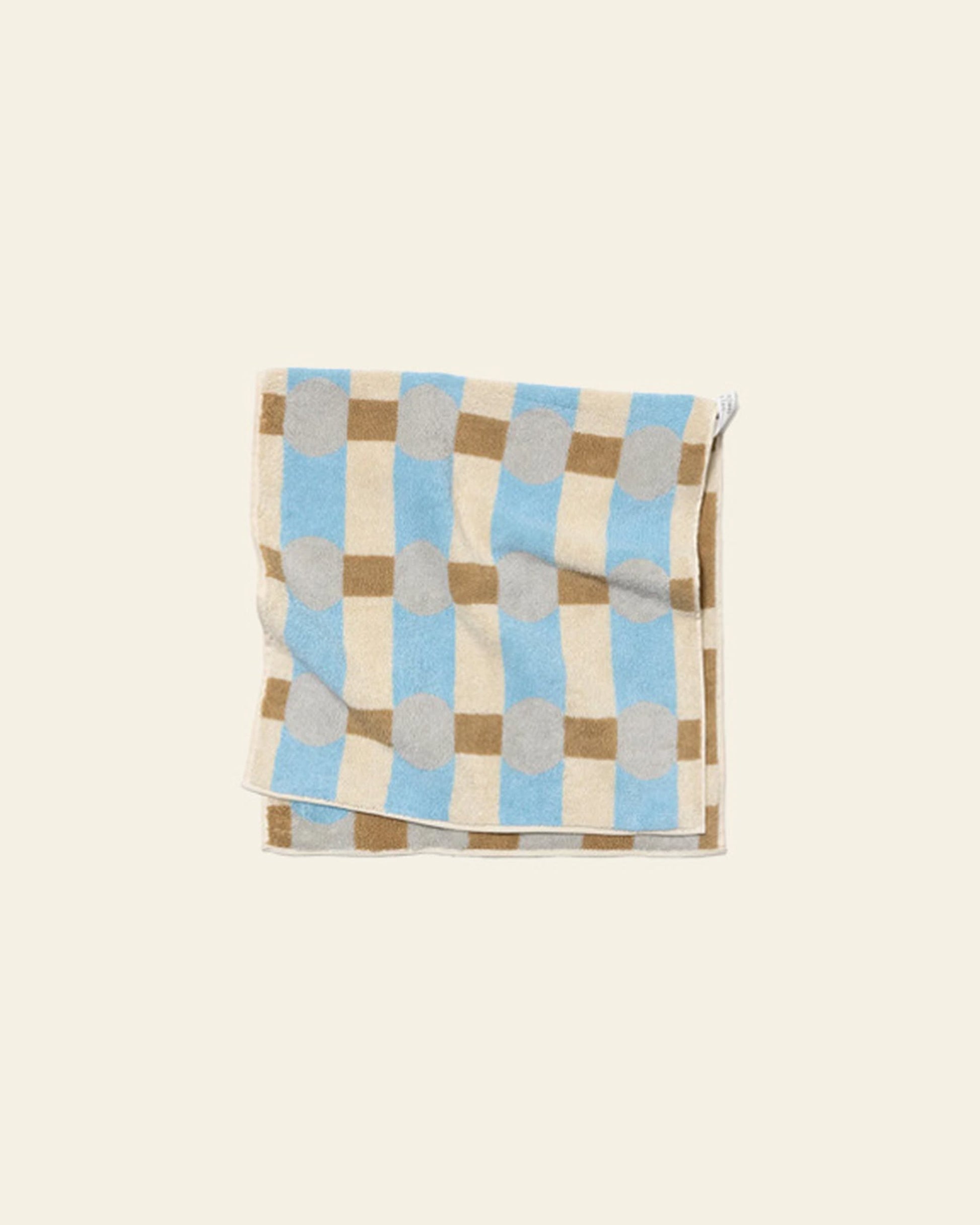 The WARMGREY TAIL Dot Check Face Towel by WARMGREY TAIL is a quality cotton terry towel featuring blue, beige, brown, and gray checkered and polka dot patterns on an off-white background.