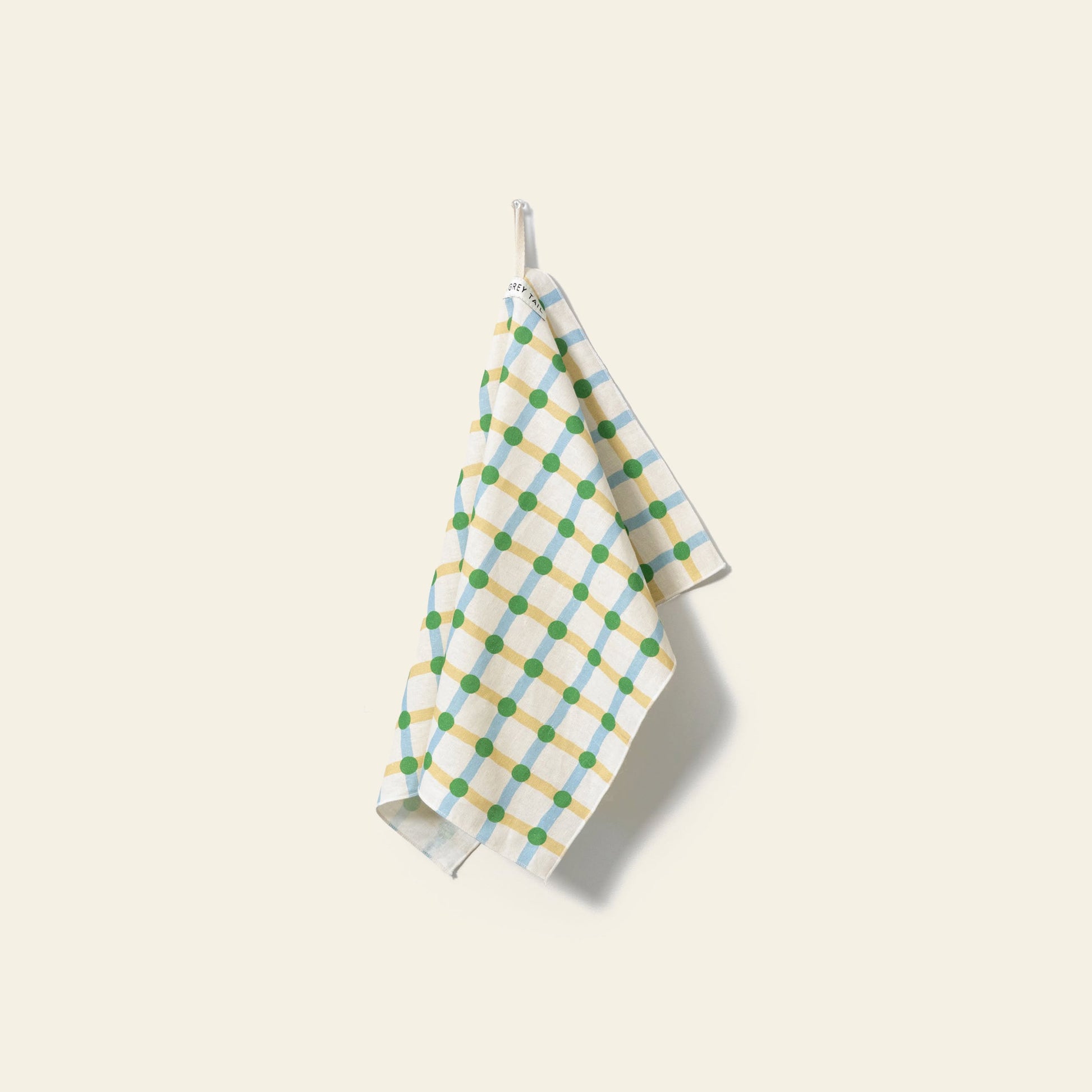The WARMGREY TAIL Dot Check Kitchen Cloth 2 features blue and green checks with yellow lines, hanging from a small hook against a light background—a practical and stylish accessory for any kitchen.