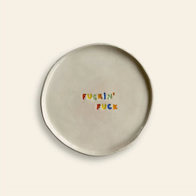 The Wobbly Studio Mini Plate - Fuckin Fuck is a handcrafted white ceramic plate featuring FUCKIN FUCK in colorful letters—a playful, bold piece by Wobbly Studio for fans of cheeky designs.