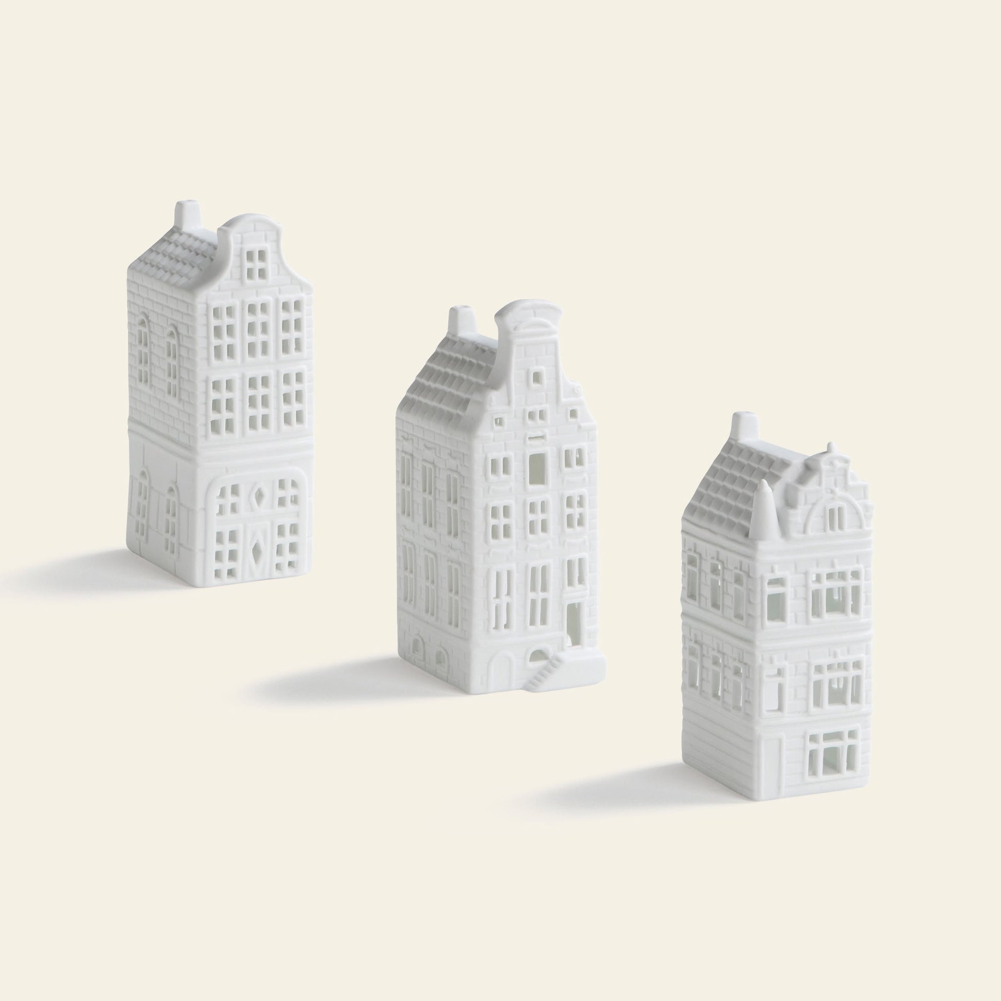 The &klevering Canal House #4 Tealight Set of 3 features small, white tealight holders with detailed windows and accents, arranged upright and ideal for adding a touch of Amsterdam décor to your home.