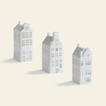 The &klevering Canal House #4 Tealight Set of 3 features small, white tealight holders with detailed windows and accents, arranged upright and ideal for adding a touch of Amsterdam décor to your home.