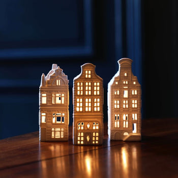 The &klevering Canal House #4 Tealight, Set of 3 by &klevering features ceramic canal house holders with glowing windows, casting a cozy Amsterdam vibe on any surface.