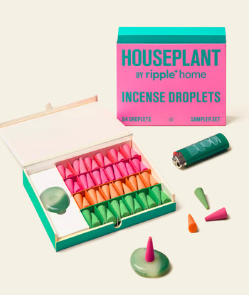 Experience the ripple+ Houseplant Incense Droplets Sampler Set by ripple+: a hand-rolled incense cone set in pink, orange, and green, complete with a lighter, round holder, and three cones outside the box for your aromatic pleasure.