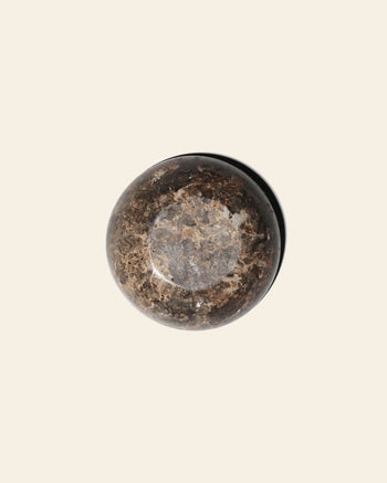 Small, circular stillgoods Luna Dish made of polished dark brown stone with swirling veining.