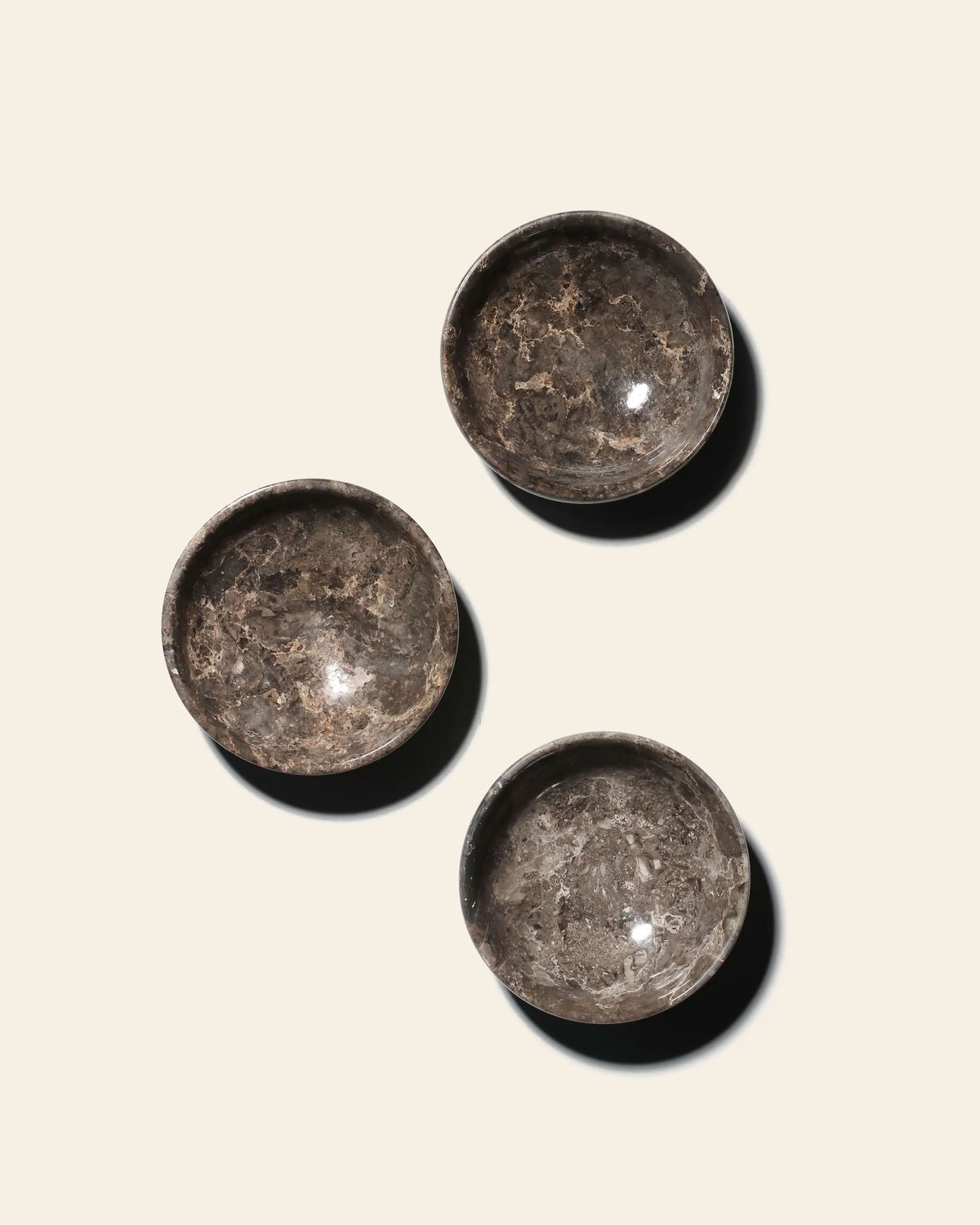 Three circular stillgoods Luna Dish trinket dishes with a marbled grey and brown pattern arranged on a light surface.