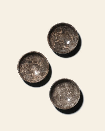Three circular stillgoods Luna Dish trinket dishes with a marbled grey and brown pattern arranged on a light surface.